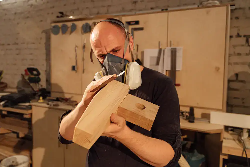 Craftsman sanding a wooden toy in the workshop