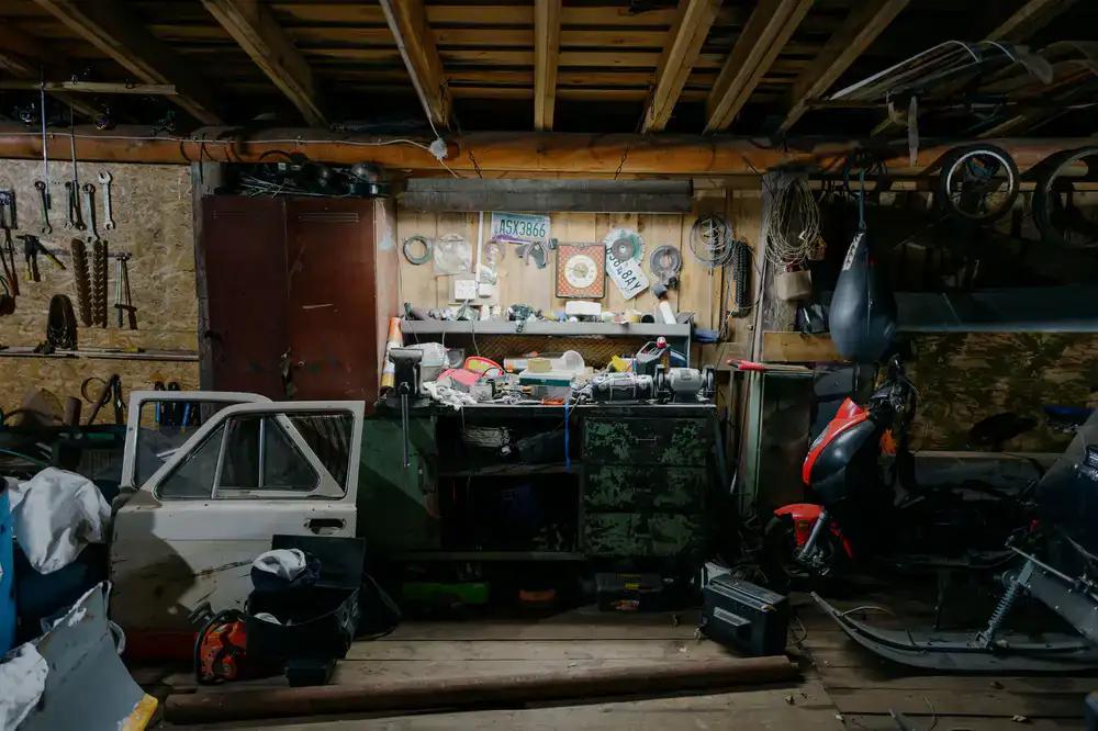A cluttered, warm wooden workbench with marionette parts and carving tools
